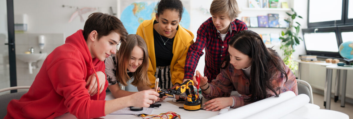 Group of students building and programming electric toys and robots at robotics classroom